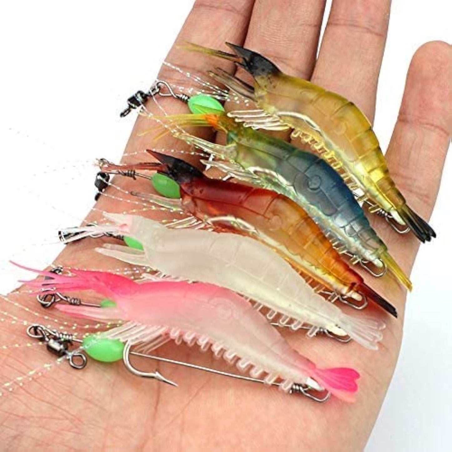 Hand holding five glow-in-the-dark shrimp lures in assorted colors for snook, redfish, and tarpon