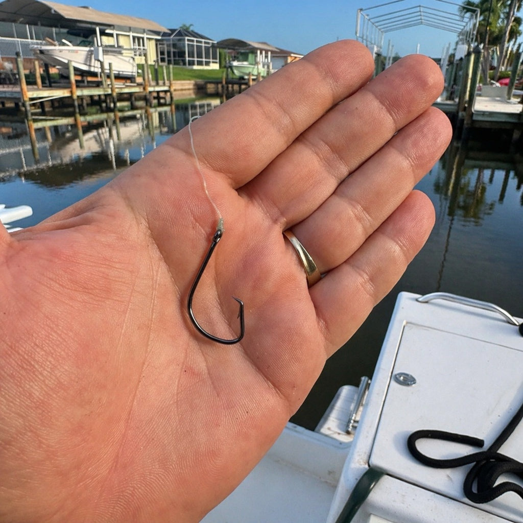 1/0 circle hook in hand with fishing line rigged on clean boat deck for saltwater fishing